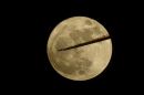 An aircraft flies past the moon over Somerset, UK as the Earth's satelite is its closest for years, producing a 'supermoon'