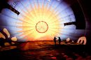 Two people inside a colourful balloon are silhouetted as the early morning sunlight strikes what is the top of the balloon as the crew prepare to inflate it at the Bristol International Balloon Fiesta, Ashton Court, Bristol