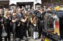 Families and friends blow kisses as the hearse slowly moves along the High Street