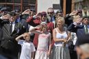Members of the public salute as the hearse drives past in the days when family did not attend to watch the cortege pass