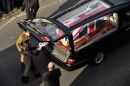 The back of a hearse is opened so a tribute can be paid to a Ghurka soldier