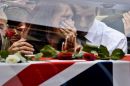 Grief overcomes a woman as she touches the glass side of the hearse
