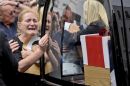 A woman reacts as she clutches a photograph and holds the hearse containing the coffin of a fallen soldier